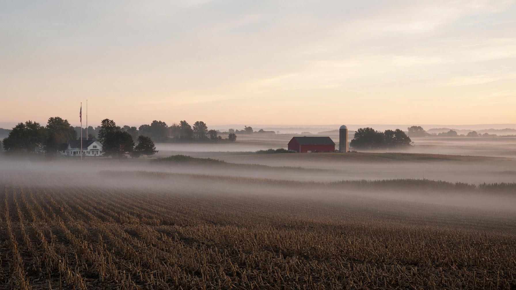 Dawn mist over Adams County farmland, barn and silo on the horizon.